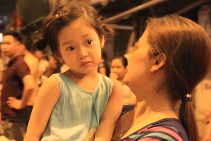 Một em bé được mẹ bế đứng đợi ông Obama.