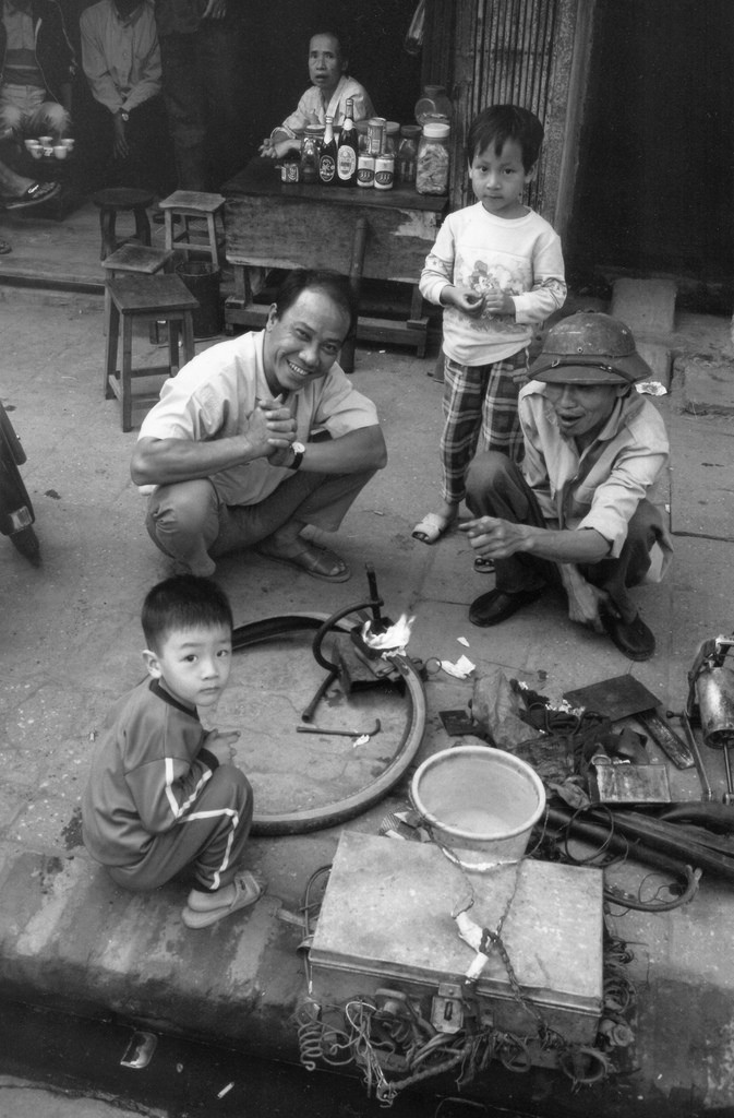 Quán trà đá và cửa hàng sửa xe đạp trên vỉa hè phố cổ.