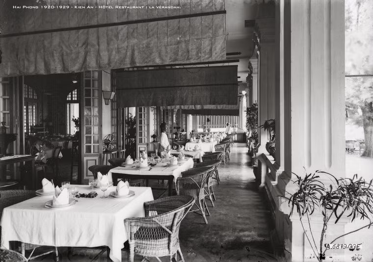 Dãy bàn ăn dọc hành lang, phía trên là các quạt trần kéo bằng tay.