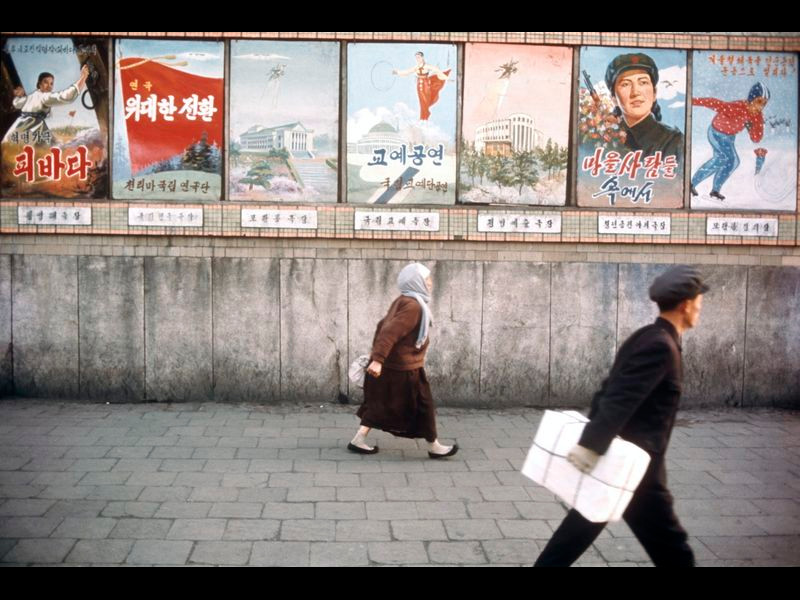 Người dân đi ngang qua các áp-phích tuyên truyền trên đường phố Bình Nhưỡng.