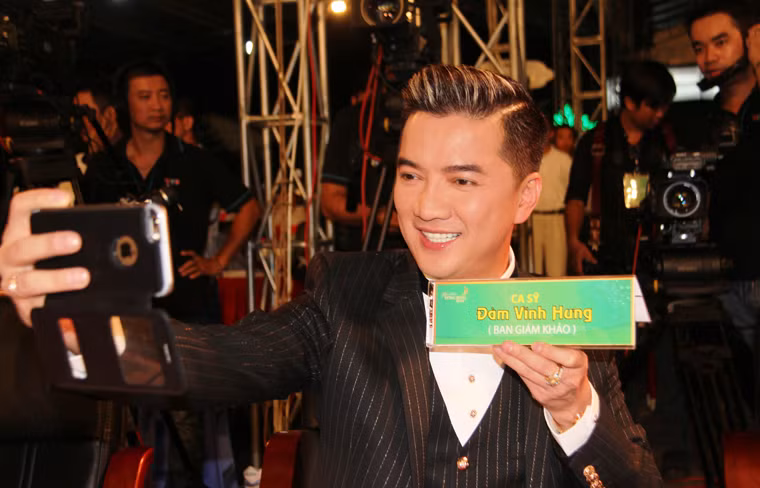 Hàng nghìn khán giả có mặt tại sân khấu đêm chung kết Hoa khôi ĐBSCL 2015 vô cùng thích thú khi nhìn thấy ca sĩ Đàm Vĩnh Hưng ngồi trên hàng ghế ban giám khảo liên tục lấy điện thoại chụp hình "tự sướng".