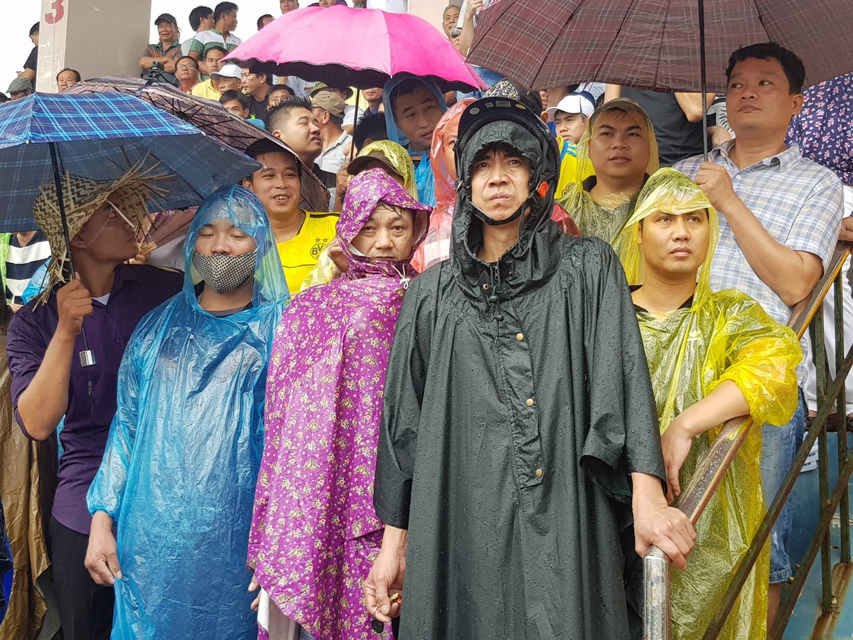 Trong sân nhiều người đội mưa xem các kháp đấu.