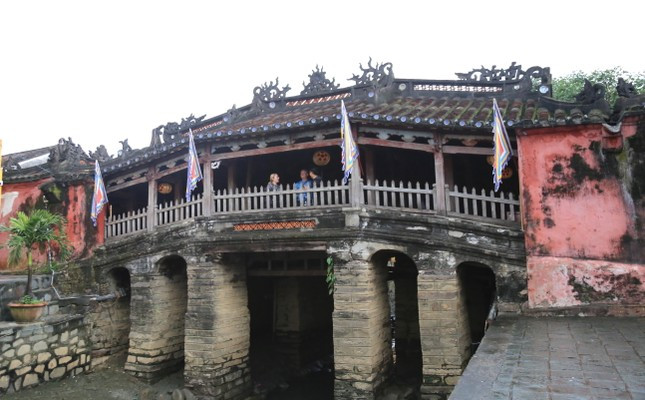 Hiện phần mố trụ phía dưới cầu hiện được chống đỡ bằng một số thanh gỗ. Khi trùng tu sẽ gia cố bơm keo, vữa vào các vết nứt, nạo vét bùn, vệ sinh và đổ bê tông gia cố móng. (Ảnh: Tiền Phong).