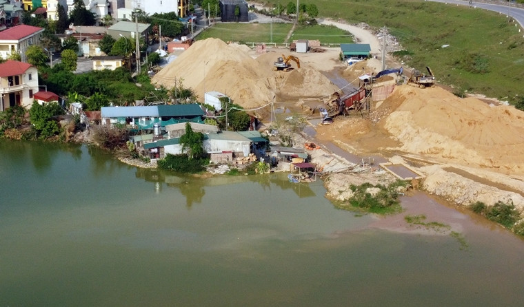 Một góc ao loang lổ màu nước lạ, chảy xuống từ khu máy sàng đất của bãi tập kết.
