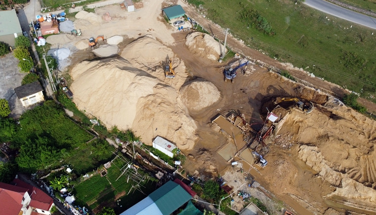 Tại bãi tập kết không có biển hiệu, hay thông tin của bất kỳ doanh nghiệp, cá nhân nào. Ở đây chỉ có những đống đất, cát được chất cao như “núi”. Cùng với đó là những chiếc máy múc hoạt hết công suất, xe ô tô vận chuyển ra vào liên tục. Theo người dân, đất, cát ở bãi này được đưa từ nơi khác về.