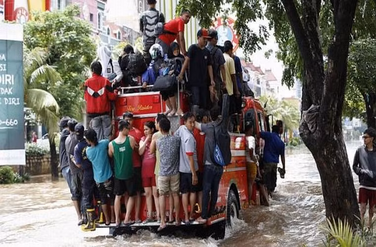 Người dân di chuyển bằng cách leo lên chiếc xe cứu hỏa khi chiếc xe này băng qua con phố lụt lội ở Jakarta ngày 10/2/2015.