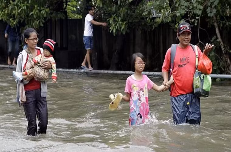 Người mẹ bế con băng qua dòng nước cùng gia đình ở Jakarta, Indonesia ngày 10/2/2015.