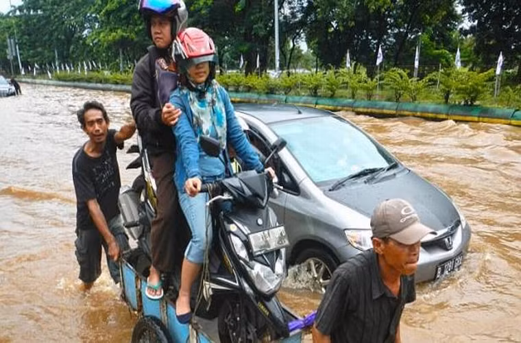 Cặp đôi này thì đang bảo vệ bản thân và tài sản bằng cách cột chặt xe máy lên 1 chiếc xe chở đồ và ngồi trên yên xe để 2 người khác đẩy qua dòng nước lũ ngày 10/2/2015.