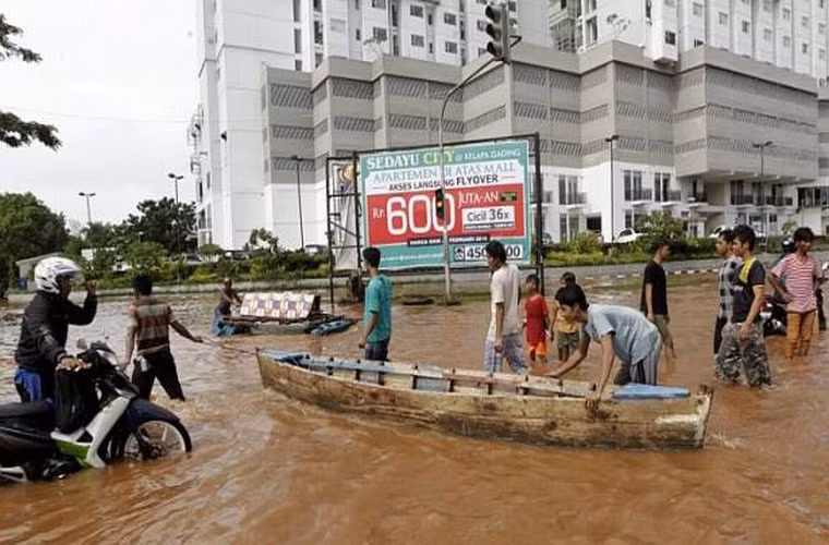 Người dân đẩy chiếc thuyền gỗ băng qua dòng nước ở Jakarta, Indonesia ngày 10/2/2015..