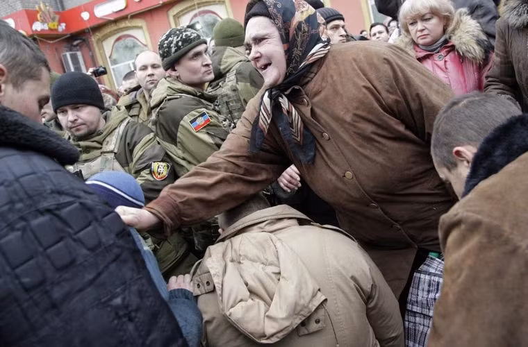 1 người phụ nữ yêu cầu các tù nhân chiến tranh thuộc lực lượng vũ trang Ukraine phải quỳ gối gần khu vực chiếc xe buýt bị bắn phá khi những người này đang bị các thành viên lực lượng ly khai thuộc nhà nước Cộng hòa Nhân dân Donetsk bắt đi diễu phố ngày 22/1/2015.