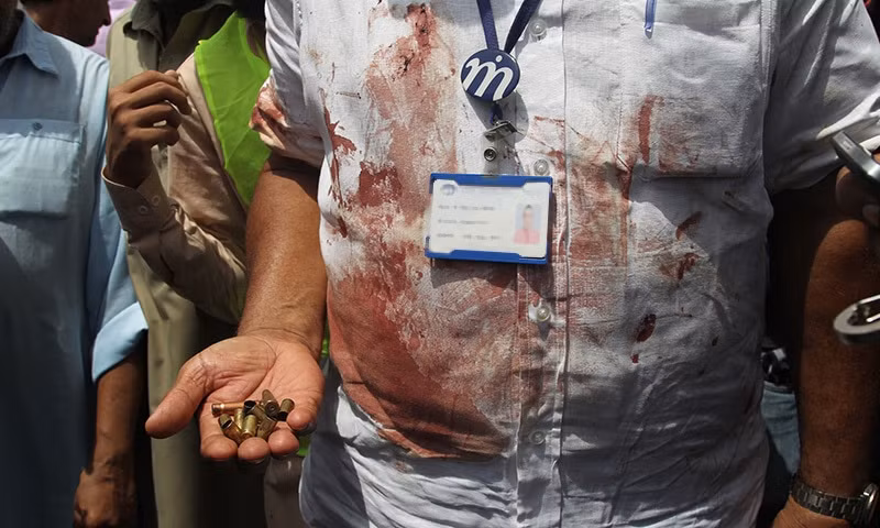 Một nhân viên cứu hộ đang cầm trên tay những vỏ đạn thu thập được từ hiện trường vụ tấn công xe bus tại Karachi, Pakistan vào ngày 13/5.