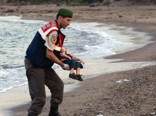 Cảnh sát bế thi thể của bé Aylan dạt vào bờ.