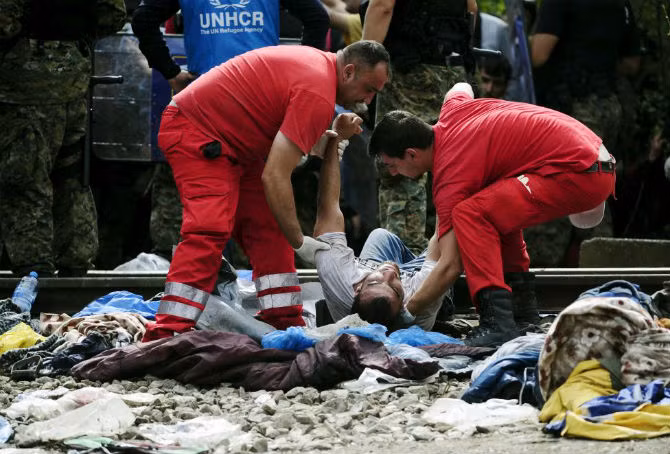 Các nhân viên của Hội Chữ thập đỏ giúp đỡ một di dân bị ngất ở Gevgelija ngày 22/8.
