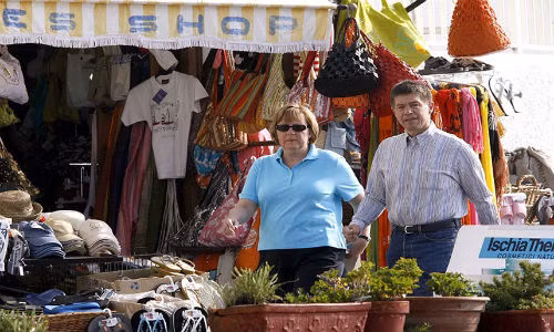 Thủ tướng Đức Angela Merkel đứng bên ngoài một cửa hàng bán đồ lưu niệm trên đảo Ischia, Italy.