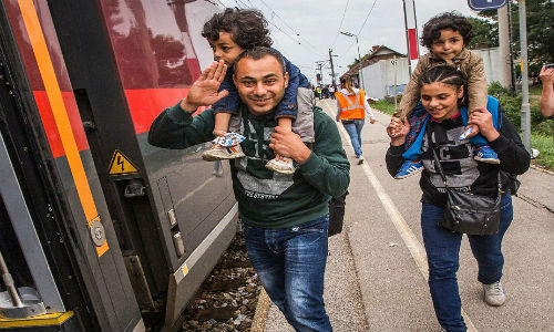 Giữa cuộc khủng hoảng di cư thế giới, một gia đình di dân vui mừng khi lên được tàu tại Nickelsdoft, Áo để tới Munich, Đức.