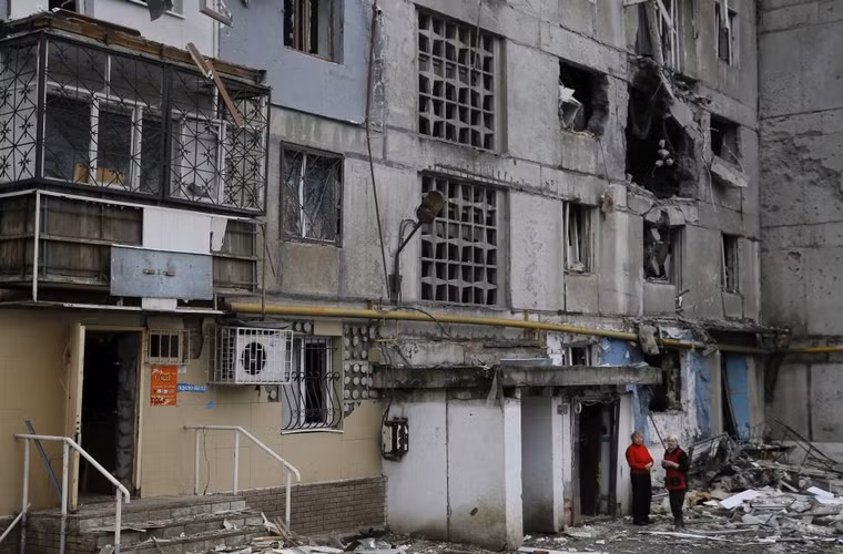 2 người phụ nữ đứng gần khu tập thể hoang tàn .