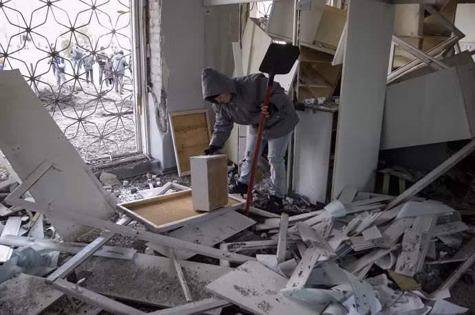 Một người phụ nữ đang dọn đống đổ nát trong một bệnh viện sau cuộc pháo kích.