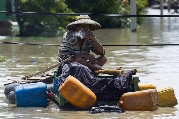 Một người dân Myanmar hút thuốc trên một chiếc bè tự chế.