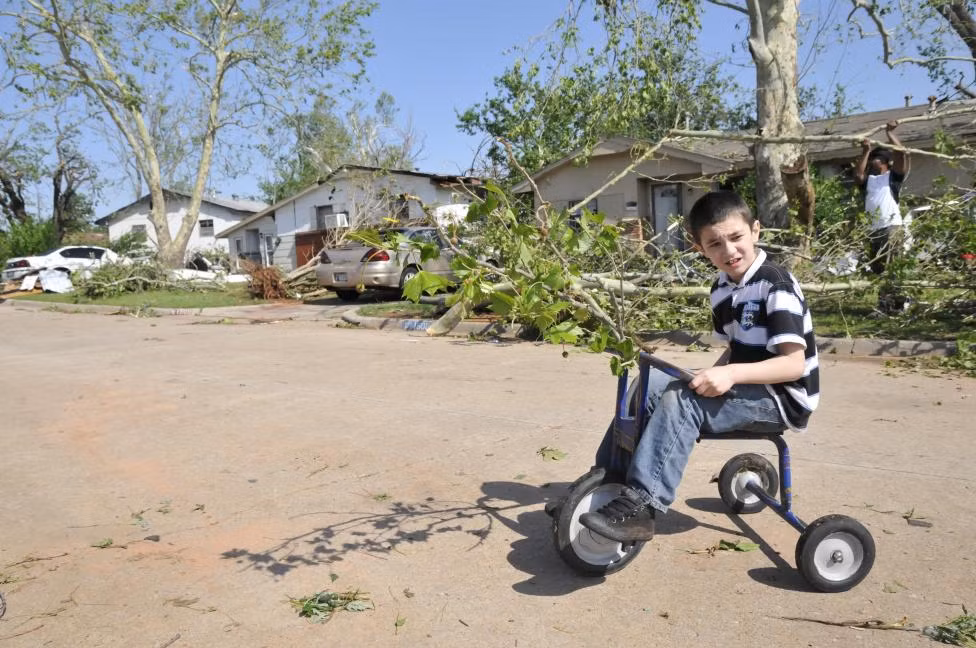 Bên cạnh cậu bé là những cành cây bị quật gãy trong cơn lốc xoáy ở Oklahoma ngày 7/5/2015.
