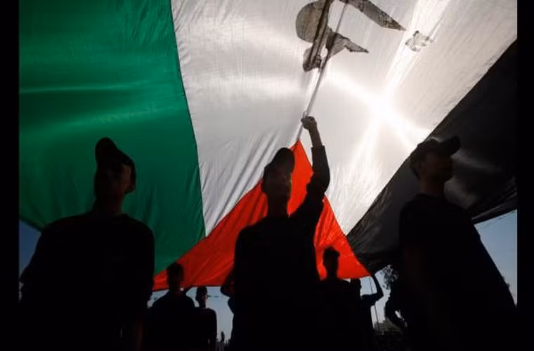 Các học viên trại huấn luyện đứng tụm dưới lá cờ Palestine.