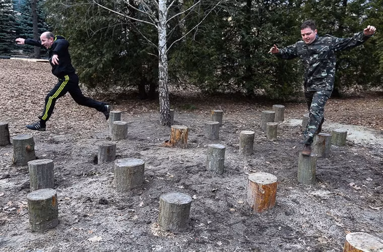 Những người tham gia bài tập nhảy trên gốc cây trong cuộc đua vượt chướng ngại vật.