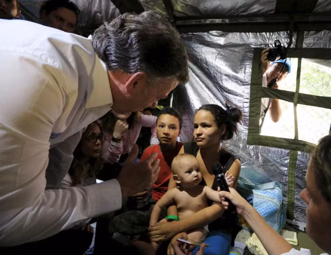 Tổng thống Colombia Juan Manuel Santos thăm hỏi một người phụ nữ vừa bị trục xuất từ Venezuela trong túp lều tạm bợ ở Cucuta, Colombia.