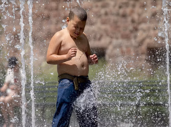 Em bé tắm dưới đài phun nước Bosque ở công viên Battery, New York, Mỹ ngày 20/7/2015.