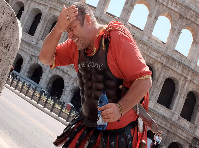 Một nghệ sĩ đường phố trong trang phục của người La Mã cổ đại hắt nước vào người để giải tỏa cơn nóng trước một đấu trường ở Rome, Italy, ngày 17/7/2015.