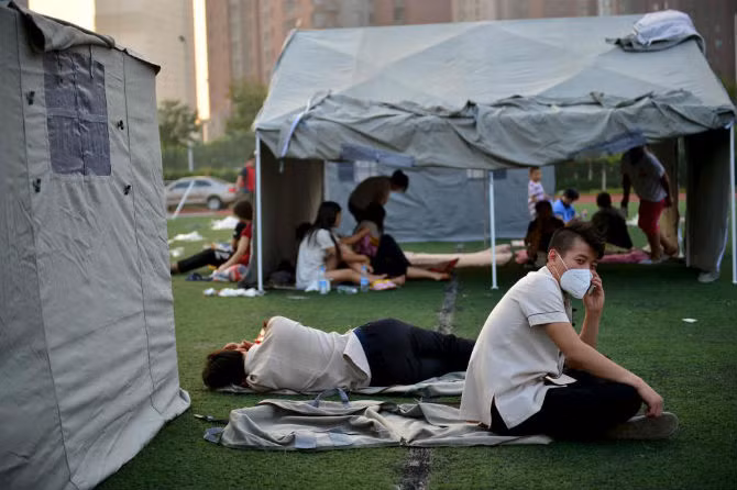 Một người đàn ông đeo khẩu trang trong khi những người khác nằm vạ vật ngoài trời sau vụ nổ.