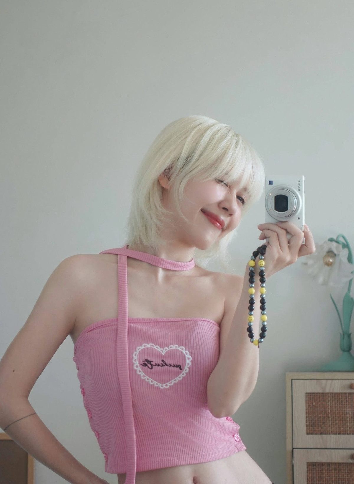 Cô diện một chiếc áo croptop hồng pastel cut-out phá cách, điểm nhấn là chi tiết thêu chữ “Sweet” bên trong khung trái tim, kết hợp cùng phần dây quàng cổ tạo nên vẻ vừa đáng yêu vừa nổi loạn nhẹ nhàng.