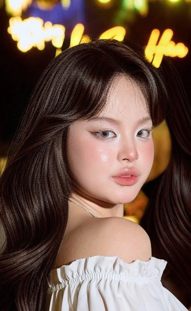 Điểm đặc biệt là mái tóc dài uốn sóng nhẹ - biểu tượng cho vẻ đẹp dịu dàng, đằm thắm, kết hợp cùng lớp trang điểm nhẹ nhàng với sắc hồng nude, tôn lên đôi mắt sắc sảo và bờ môi chúm chím. Tổng thể phong cách của Suli thể hiện sự trưởng thành, tự tin, đồng thời vẫn giữ được nét thuần khiết đúng tuổi.