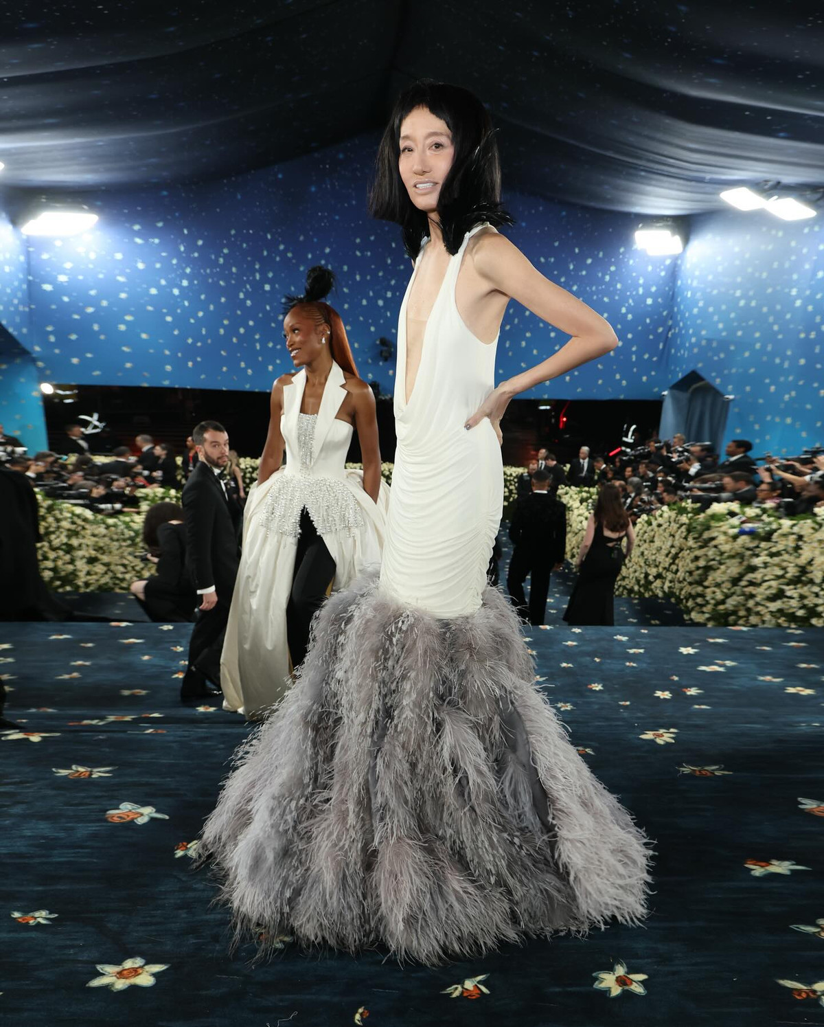 Trong bộ váy trắng cắt xẻ táo bạo, phần chân váy phủ lông vũ màu xám bồng bềnh và điểm nhấn là mái tóc đen cắt ngắn lạ mắt, Vera Wang vừa thanh lịch, vừa nổi loạn – đúng tinh thần của Met Gala.