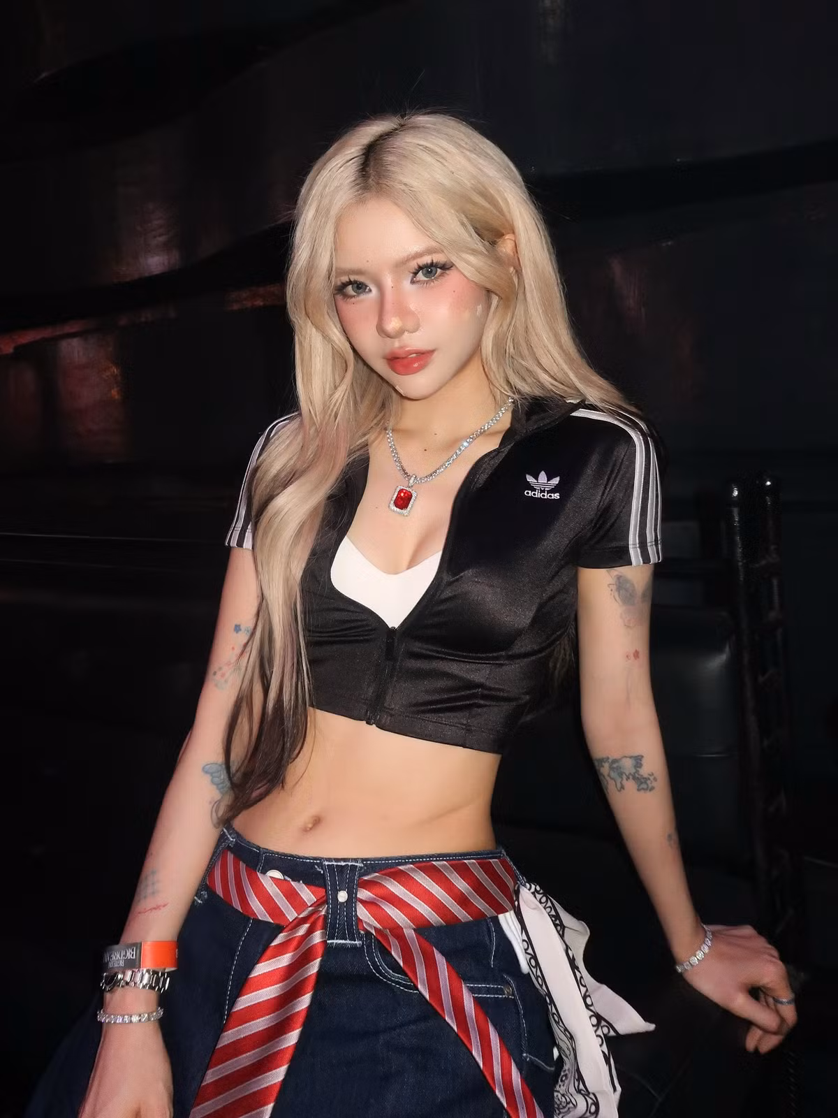 Điểm nhấn không thể bỏ qua là đôi boots đỏ nổi bật cùng khăn caro buộc hờ quanh eo, tạo nên tổng thể đậm chất “girl hệ chiến” - mạnh mẽ, phá cách nhưng vẫn cực kỳ thời thượng.