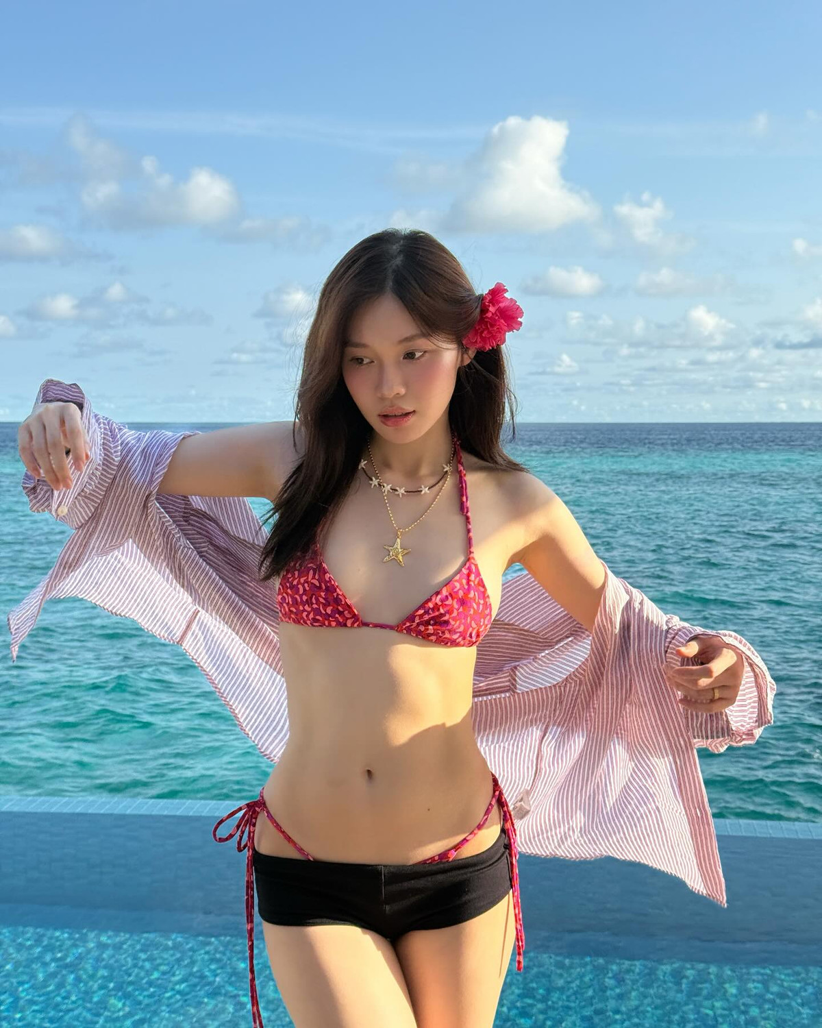 Cô nàng khéo léo mix cùng áo sơ mi kẻ sọc dáng rộng khoác hờ hững và chuỗi vòng cổ hình sao biển cùng hoa tai biển mang hơi hướng tropical, tạo nên tổng thể vừa phóng khoáng vừa nữ tính.