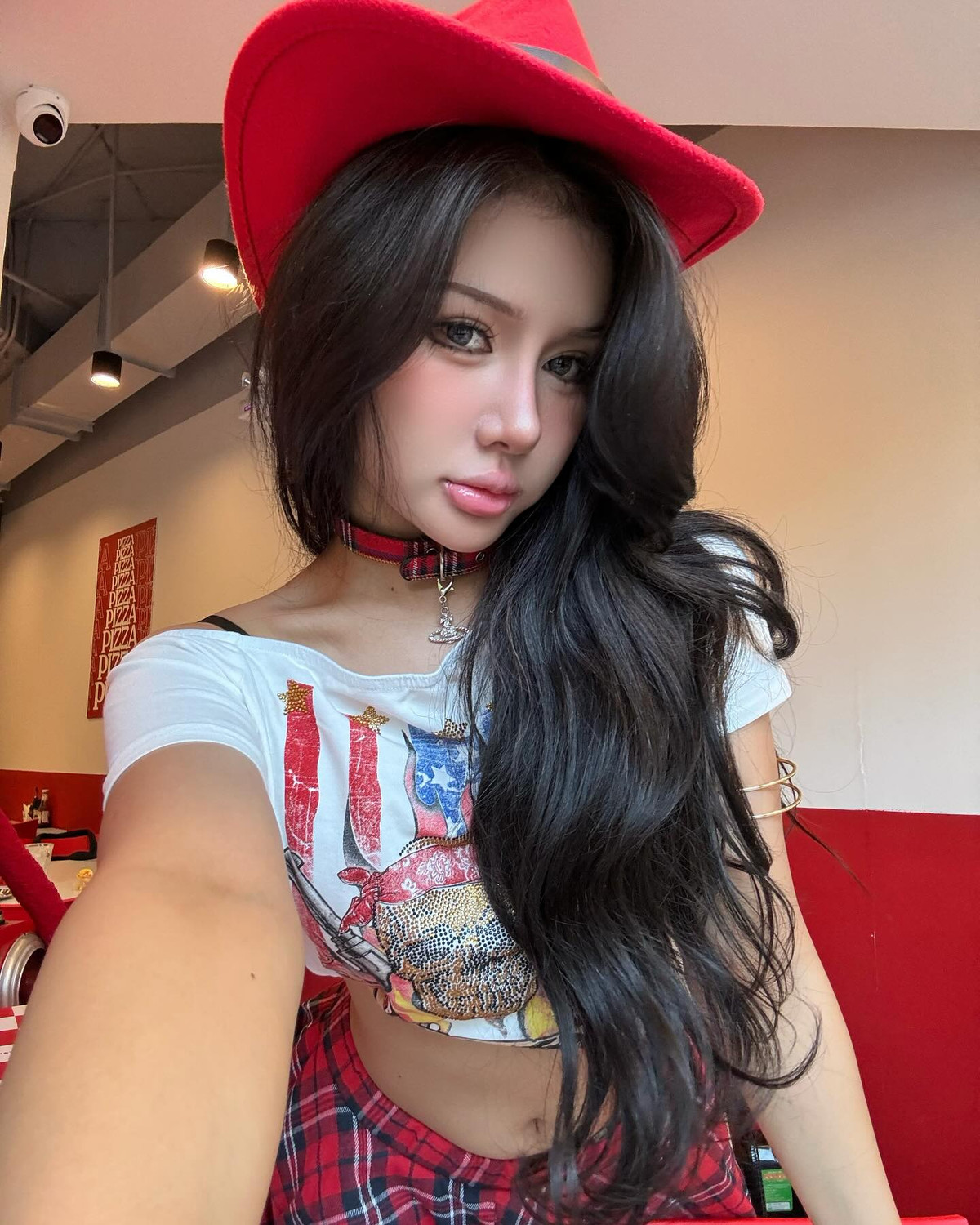 Phụ kiện không thể thiếu là mũ cao bồi đỏ rực, giúp tăng sức hút thị giác và khẳng định cá tính thời trang nổi bật.