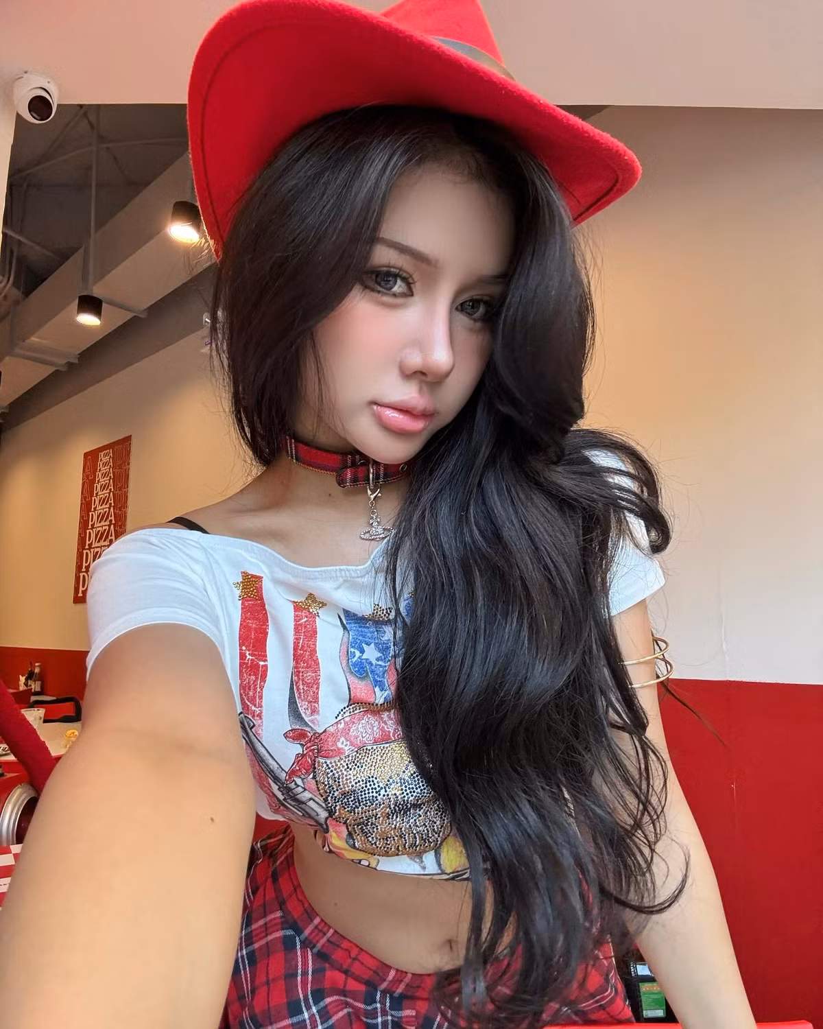 Phụ kiện không thể thiếu là mũ cao bồi đỏ rực, giúp tăng sức hút thị giác và khẳng định cá tính thời trang nổi bật.