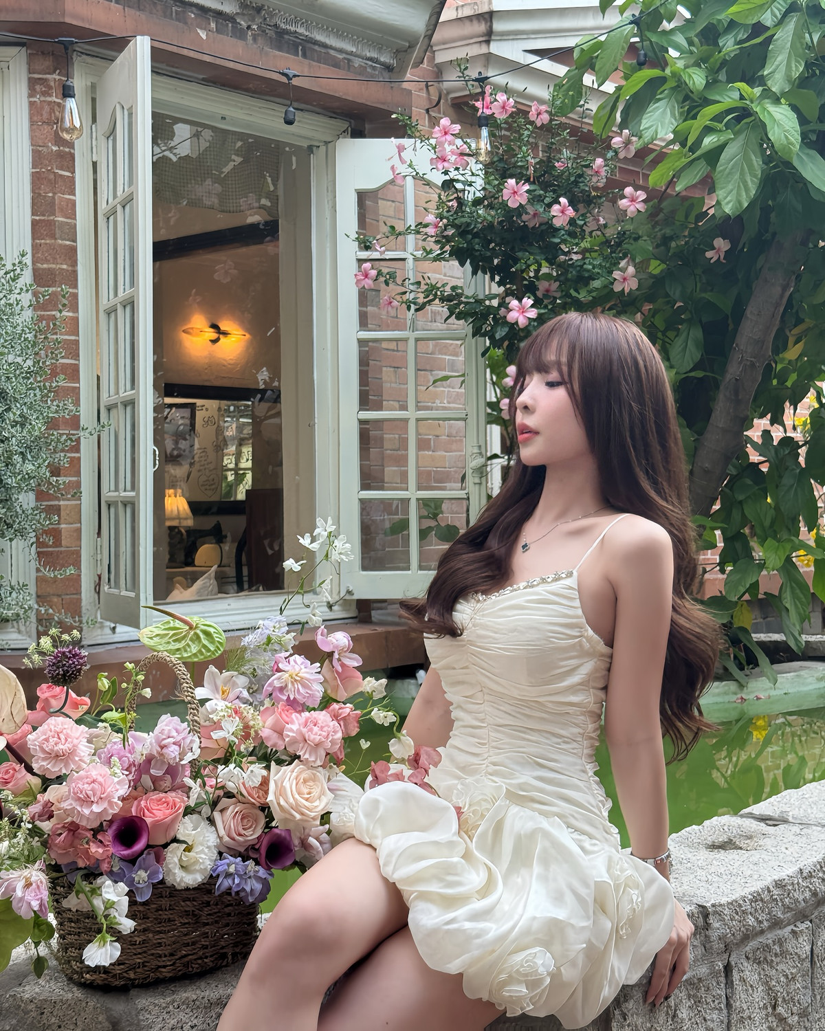 Viền cổ đính đá sáng nhẹ lấp lánh càng làm tăng vẻ thanh thoát, sang chảnh cho tổng thể, trong khi phần chân váy tạo phồng nhẹ với họa tiết hoa ẩn hiện, làm nổi bật hình ảnh “nàng thơ giữa vườn hoa”.