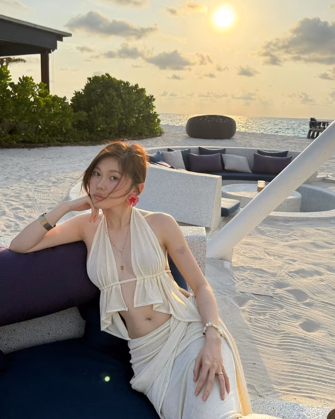 Không chọn bikini truyền thống, cô nàng diện một set đồ biển màu kem nhã nhặn nhưng đầy phá cách, gồm áo yếm cách điệu khoe lưng trần nuột nà, kết hợp cùng chân váy quấn hờ tinh tế, tạo nên tổng thể vừa mềm mại, vừa gợi cảm đến nghẹt thở.