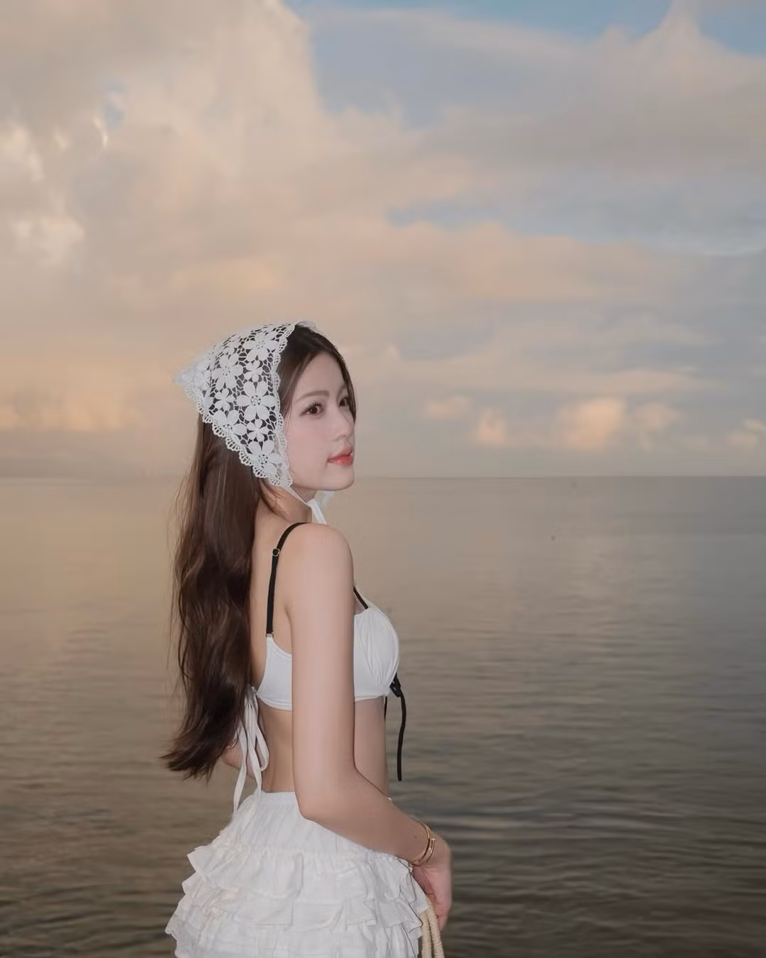 Màu trắng tinh khôi không chỉ tôn lên làn da trắng mịn mà còn mang lại cảm giác nhẹ nhàng, tinh khiết, rất phù hợp với không gian biển lúc bình minh.