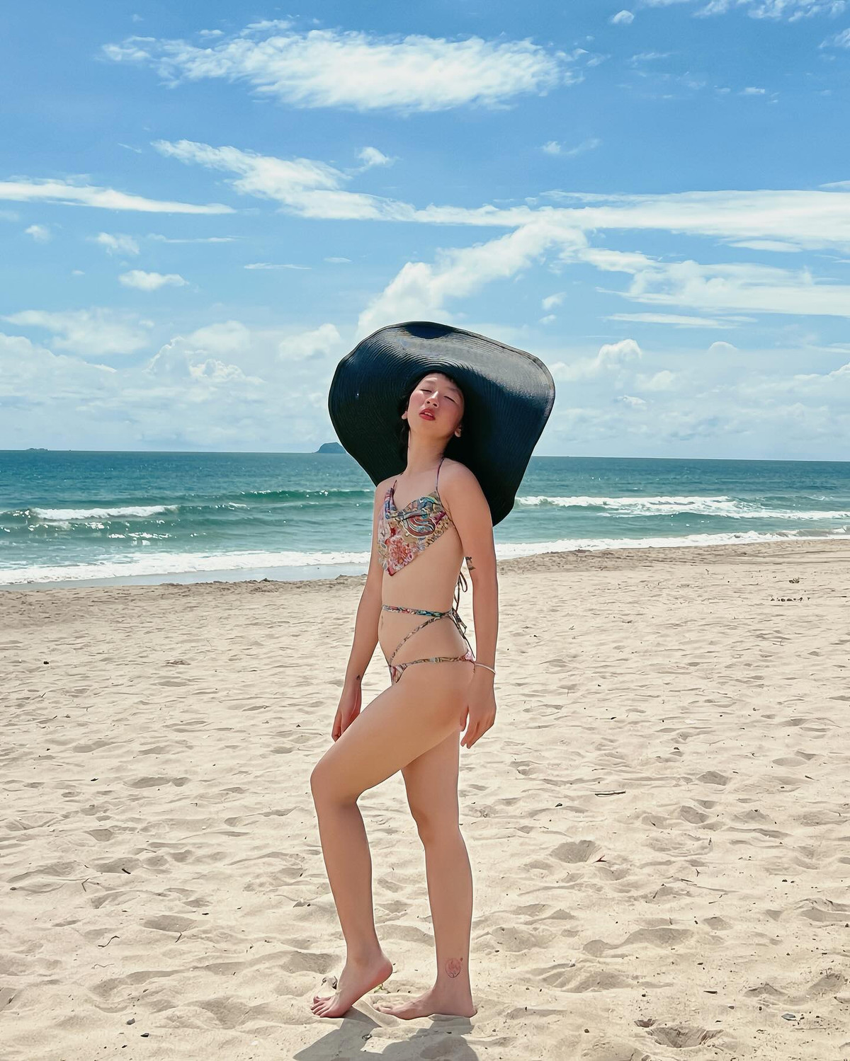 Diện bộ bikini họa tiết rực rỡ kết hợp cùng chiếc mũ rộng vành đen ấn tượng, Trang Hý không ngại tạo dáng đầy tự tin giữa nắng vàng, biển xanh.