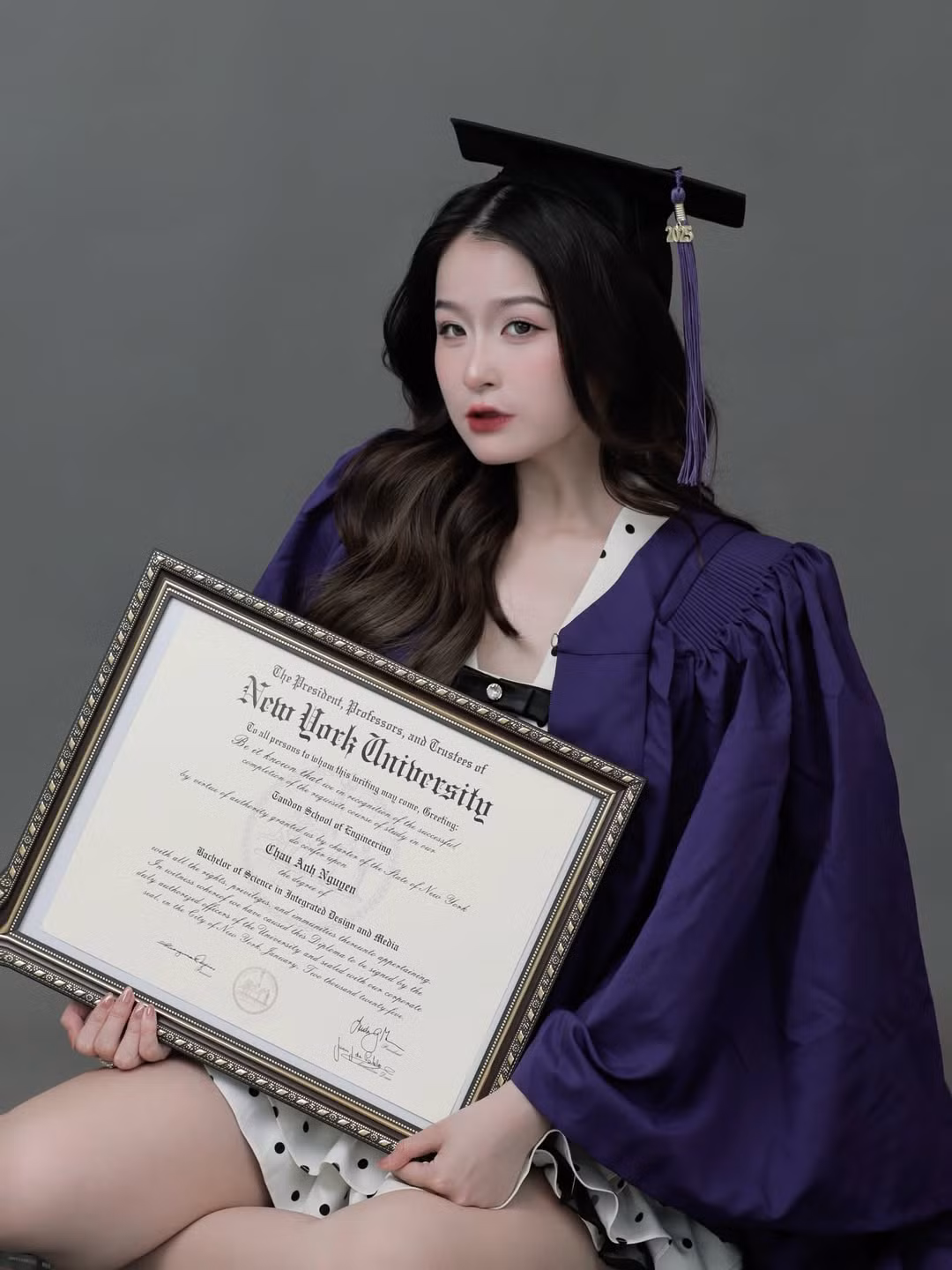 Trong bức ảnh, Chao khoác áo choàng tím truyền thống cùng mũ cử nhân, tay cầm bằng tốt nghiệp đầy tự hào. Tuy nhiên, điểm khiến cư dân mạng "chia phe" chính là bộ váy ngắn chấm bi phối ren quyến rũ bên trong lớp áo choàng.