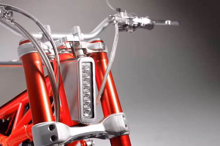 Các dây dẫn của tay phanh, côn, ga... được giấu gọn gàng trong các ống dây thép. Toàn bộ phần đầu xe nay chỉ còn là một hàng đèn pha LED đặt dọc cực mỏng, với bề dày chỉ ngang cổ phốt của khung. Chúng ta sẽ quay trở lại nói về lý do khiến 2 xưởng độ lựa chọn thiết kế này một lúc nữa.