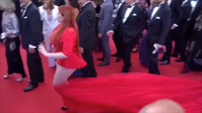 Nhưng sau khi tạo dáng, cô di chuyển bước đi thì bị một người đàn ông giẫm vào đuôi váy. Phần chân váy bị kéo tuột ra trước sự chứng kiến của hàng trăm người.