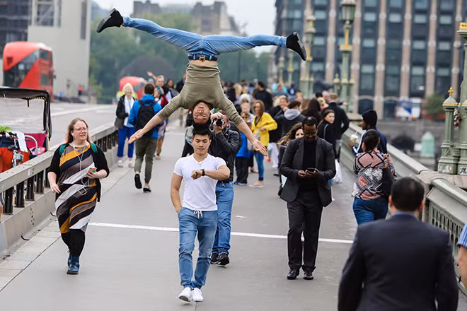 Quốc Cơ - Quốc Nghiệp đi qua những địa danh nổi tiếng tại London với động tác chồng đầu, nhằm giới thiệu nghệ thuật xiếc Việt Nam đến người dân Anh quốc.