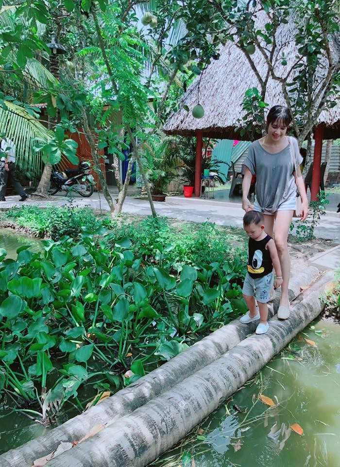 Hai mẹ con dắt nhau đi qua cây cầu dừa - một phong cảnh không thể thiếu ở không gian miền quê sông nước.