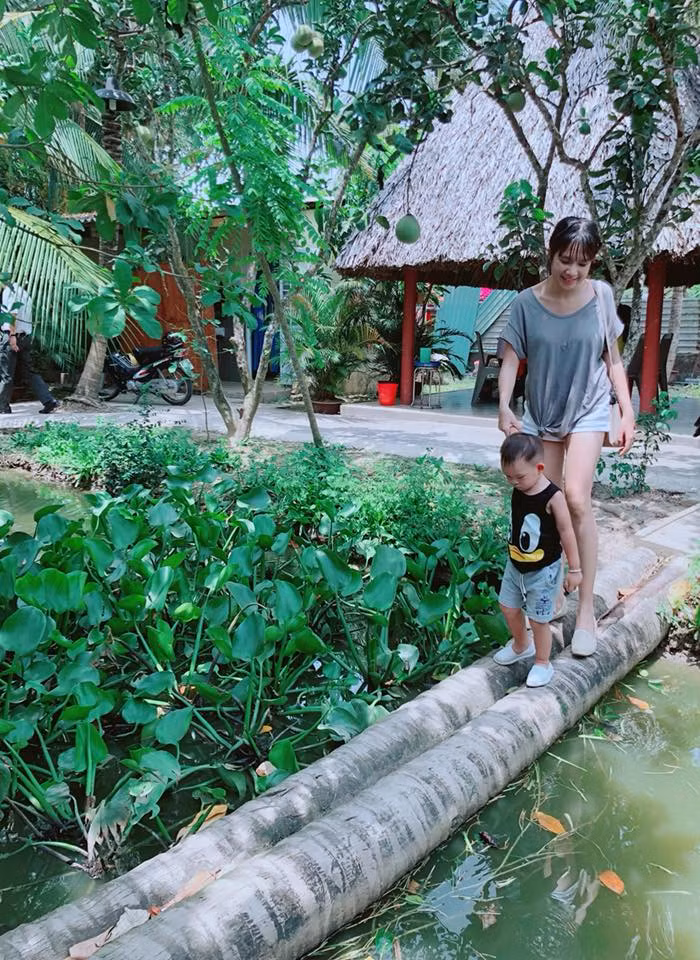 Hai mẹ con dắt nhau đi qua cây cầu dừa - một phong cảnh không thể thiếu ở không gian miền quê sông nước.