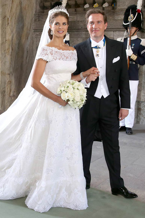 Công chúa Thụy Điển Madeleine chọn váy cưới tinh xảo của nhà mốt lừng danh Italy - Valentino Garavani. Váy cưới của Madeleine được may bằng vải lụa in hoa hồng và phần thân trên đắp ren thêu tay. Chiếc váy có cổ thuyền rộng và lưng khoét chữ V để khoe bờ vai cô dâu mà vẫn đảm bảo sự thanh lịch, sang trọng.