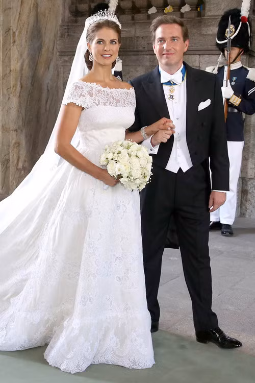 Công chúa Thụy Điển Madeleine chọn váy cưới tinh xảo của nhà mốt lừng danh Italy - Valentino Garavani. Váy cưới của Madeleine được may bằng vải lụa in hoa hồng và phần thân trên đắp ren thêu tay. Chiếc váy có cổ thuyền rộng và lưng khoét chữ V để khoe bờ vai cô dâu mà vẫn đảm bảo sự thanh lịch, sang trọng.