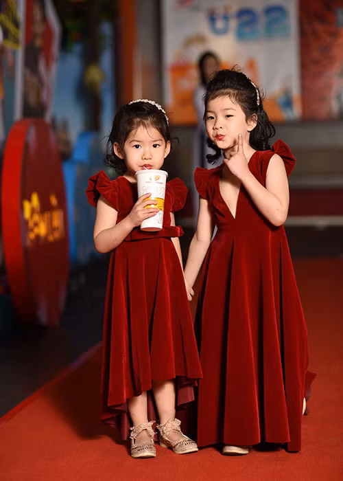 Hai nhóc tì ăn mặc ton-sur-ton với mẹ và tạo dáng đáng yêu trên thảm đỏ.