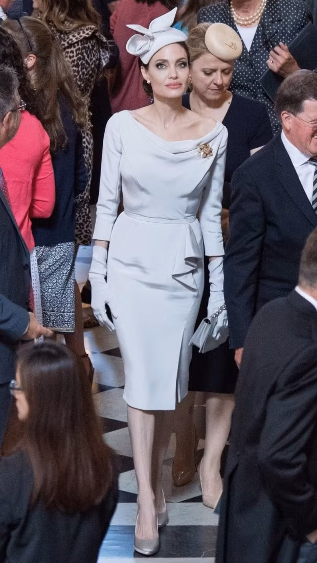 Giữa ồn ào thị phi, vào ngày 28/6, Angelina Jolie đã có mặt ở thánh đường St. Paul để tham dự lễ kỷ niệm 200 năm Huân chương Thánh Michael và Thánh George. Xuất hiện trong trang phục đầm peplum trắng ngà, với kiểu búi tóc gọn gàng và đội mũ kiểu quý tộc đồng màu với bộ cánh thanh lịch, Angelina Jolie thu hút mọi ánh nhìn.
